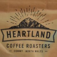 The Heartland Coffee Roasters logo, from one of its bags of coffee, showing the sun setting behind the mountains of North Wales.