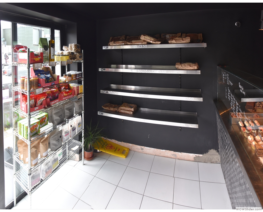 Inside, to the left of the door, is a set of retail shelves, with the bread...
