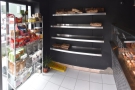 Inside, to the left of the door, is a set of retail shelves, with the bread...